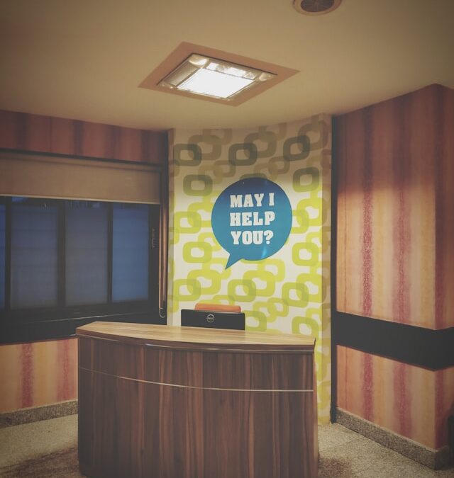 Empty desk with a “May I Help You?” sign symbolizing friendly support and patient assistance at Hammond Psychology & Associates.