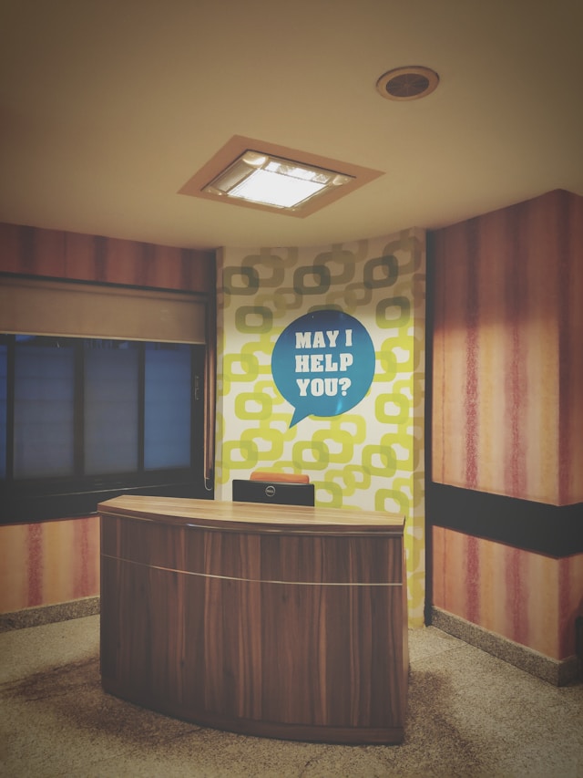 Empty desk with a “May I Help You?” sign symbolizing friendly support and patient assistance at Hammond Psychology & Associates.