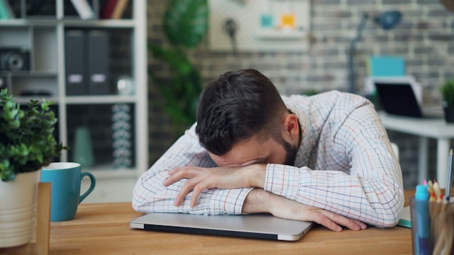 Professional sitting at desk looking exhausted while managing stress and burnout