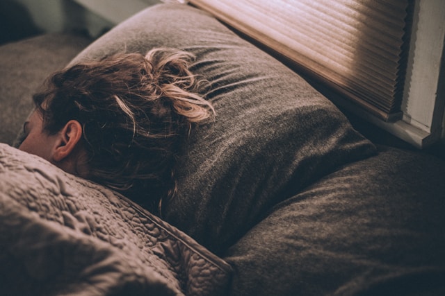 Woman sleeping in bed, representing exhaustion and mental fatigue caused by carrying a heavy mental load
