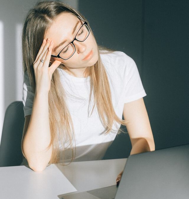 Woman sitting at laptop feeling overwhelmed by anxiety and stress