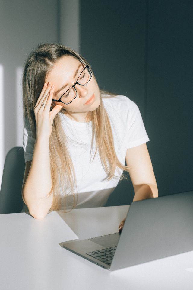 Woman sitting at laptop feeling overwhelmed by anxiety and stress