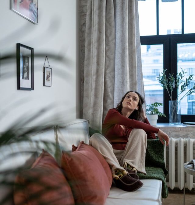 Woman sitting thoughtfully on a sofa in a living room