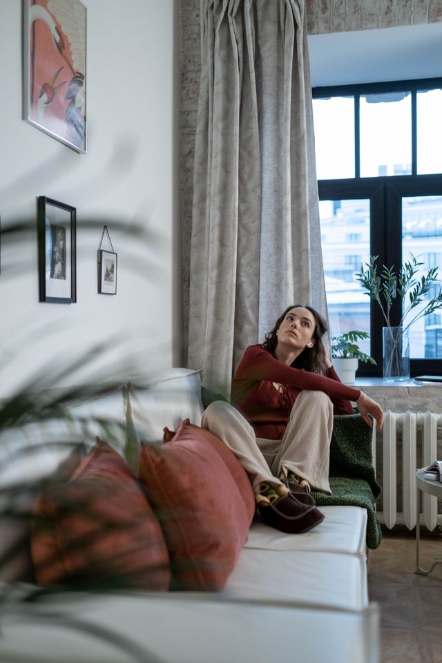 Woman sitting thoughtfully on a sofa in a living room